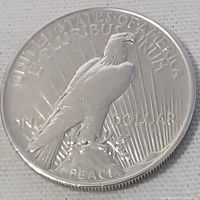 Reverse side of the 1922 Peace Silver Dollar showing eagle on rock with inscriptions and rays.
