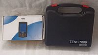 Photo showing the Belifu TENS machine box next to a black hard case labeled TENS 7000.