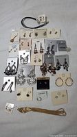 Display of assorted costume jewelry including earrings on cards, bracelet, and necklace arranged flat on a surface.