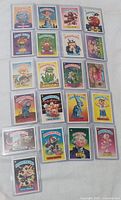 Photo showing 22 Garbage Pail Kids B cards in protective sleeves arranged in rows, featuring characters such as Garbage Bill, King-Size Kevin, Woody Alan, Dwight Bite and others.