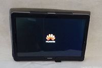 Huawei MediaPad T3 10 tablet powered on showing Huawei logo on screen inside protective case.
