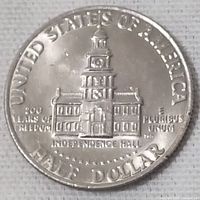 Clear top-down photo of the USA half dollar coin's reverse side showing Independence Hall and text including 'UNITED STATES OF AMERICA' and 'HALF DOLLAR'.