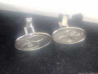 Front view of two oval sterling silver Avon cufflinks with engraved design and toggle bar fastening.