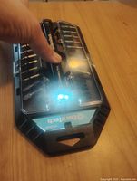 Duraltech flashlight with LED turned on, drill bits visible on both sides inside plastic case.