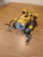 Photo of the yellow Lego submarine showing articulated arms and transparent cockpit dome on wooden surface.