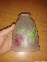 Side view of vintage frosted glass lamp shade showing embossed pink rose and green leaves design.
