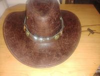 Top front view of brown Texas style hat with synthetic leather texture and metal medallion band.