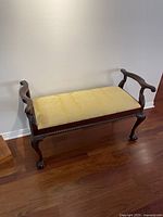 Full side view of bench showing carved arm, seat and legs