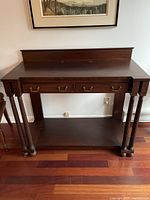 Front view of the antique mahogany buffet table showing drawer and fluted legs.