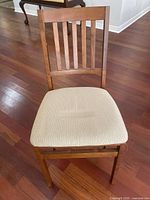 Non-folding slatted-back wooden chair with beige seat cushion