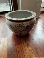 Side view of large ceramic flower pot showing colorful floral patterns and gold rim.