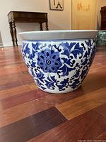 Blue and white ceramic flower pot with floral patterns on hardwood floor