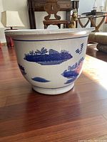 Side view of antique ceramic flower pot showing blue and white painted landscape design