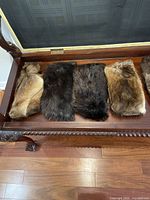 Seven vintage fur hats laid out on a wooden bench, showing different fur colors and textures.