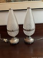 Two lamps front view on wood surface showing diamond-pattern pressed glass and metal bases