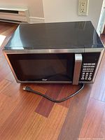Closed microwave oven showing black exterior with stainless steel handle and numeric keypad.