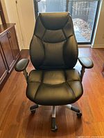 Front view showing padded seat, high backrest with stitched segments, and padded armrests.