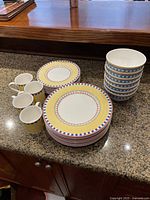 Overview of dinner plates, side plates, bowls, and mugs arranged on countertop showing design and quantity.