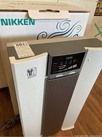 Front view of Nikken Air Purifier with original box in background
