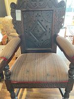 Front view showing carved high backrest with intricate patterns, diamond shape central carving, upholstered seat in striped fabric, turned front legs.