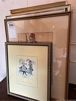 Stack of four framed artworks in varying sizes, front one has a colorful illustration.