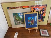 All four framed artworks displayed against a wall on a table showing size variation and color styles