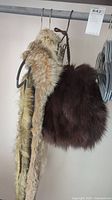 Brown round fur muff and two long fur stoles hanging on a rod