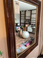 Full view of the wall mirror showing wood frame and reflection of room.