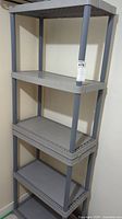 Full view of gray resin shelving unit with four shelves, showing overall structure and legs