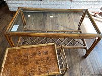 Full view of rattan coffee table with clear glass top and lap tray placed inside under the table. Floor visible beneath.