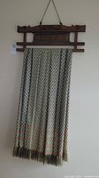 Full view of the wall hanging showing the wooden frame and the full length of the fabric with fringe at the bottom