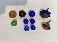 Nine colored glass knobs arranged on a white background showing color and shapes