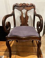 Full front view of antique handcarved wooden occasional chair with purple velvet upholstered seat showing intricate scroll armrests and cabriole legs.