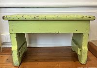 Front view of the green painted antique wooden step stool showing worn paint and construction.