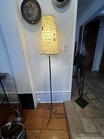 Full view of artisan floor lamp showing tall cylindrical fabric shade with black script design and slender metal stand.