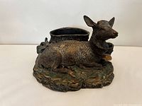 Front and side views of the handmade deer figure showing detailed texture, built-in planter, and painted base.