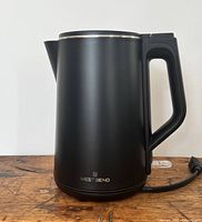 Front view of matte black Westbend electric kettle with logo visible on lower front, power cord attached to base.