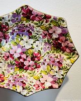 Top view of a scalloped small bowl with colorful Virginia Stock floral pattern and gold rim.