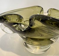 Side angle of pale apple green Czech art glass vessel showing flowing freeform shape and thickness of glass.