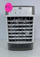 Front view of the white and gray portable air cooler showing the adjustable front grille and control panel with LED display and buttons.