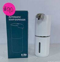 Front view of white automatic soap dispenser next to its box showing product name and 0.25 second rapid sensing feature.