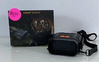 Binoculars alongside original packaging box showing night vision branding and tiger image.