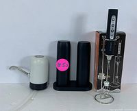 Automatic water dispenser, electric salt and pepper grinders on stand shown on a white background