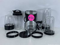 Ganiza multi-function personal blender base, blending cups of various sizes, blade attachments, and lids arranged on white surface.