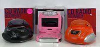 Two CD radio boomboxes (black and orange) and a pink portable DVD player with their boxes shown together.