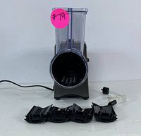 Front view of electric slicer and shredder, showing the food chute and five blade attachments laid out in front.