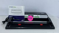 Front angled view of Ceryon vacuum sealer system with user manual and electrical power cord visible.