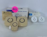 Wide shot of entire lot showing SadoTech wireless doorbell system with two receivers and one button, plus two white smart plugs in front of their packaging.