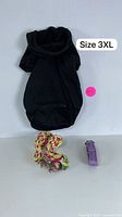 Black pet hoodie size 3XL laid flat with rope toy and purple waste bag dispenser below it.