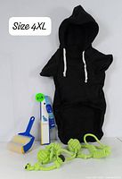 Photo showing black 4XL pet hoodie with hood, lint roller (blue handle), pet toothbrush, and two green knotted rope toys.